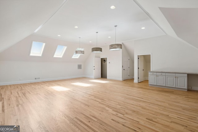 additional living space with lofted ceiling with skylight and light hardwood / wood-style flooring