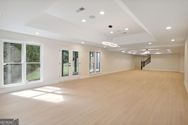 unfurnished room with a tray ceiling, a wealth of natural light, and light hardwood / wood-style flooring