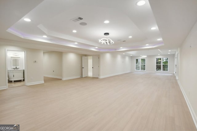 unfurnished living room with light hardwood / wood-style flooring and a tray ceiling