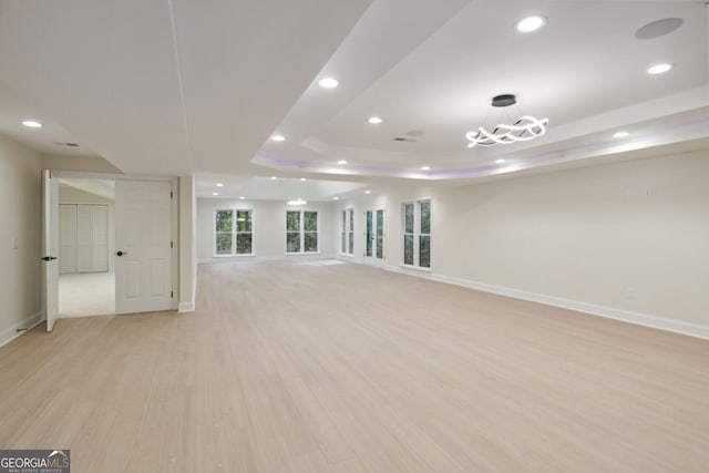 spare room with a tray ceiling and light hardwood / wood-style flooring