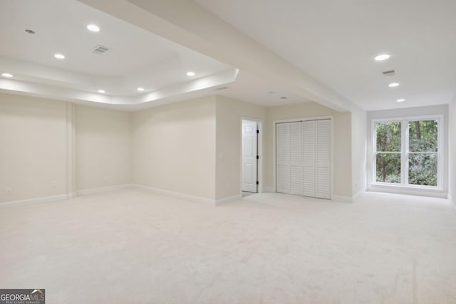 spare room featuring a tray ceiling and light colored carpet