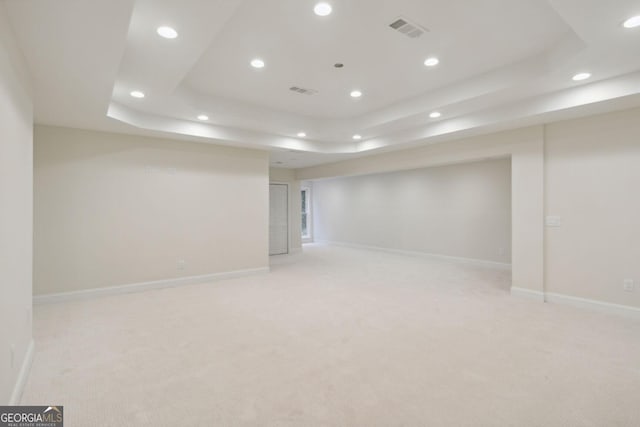 spare room with a raised ceiling and light colored carpet