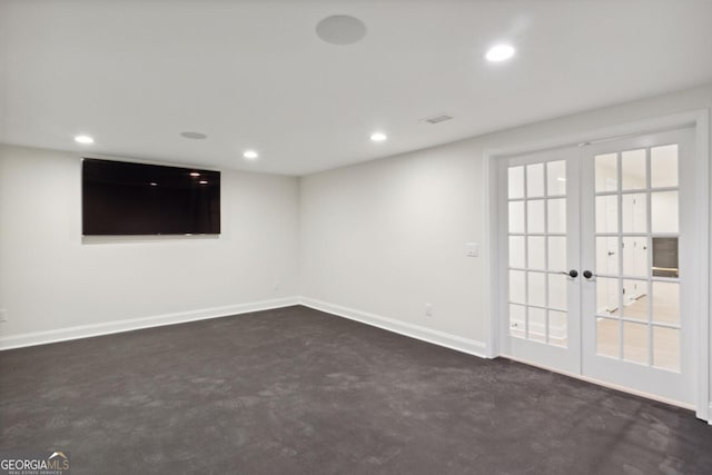 basement with french doors, a healthy amount of sunlight, and dark colored carpet