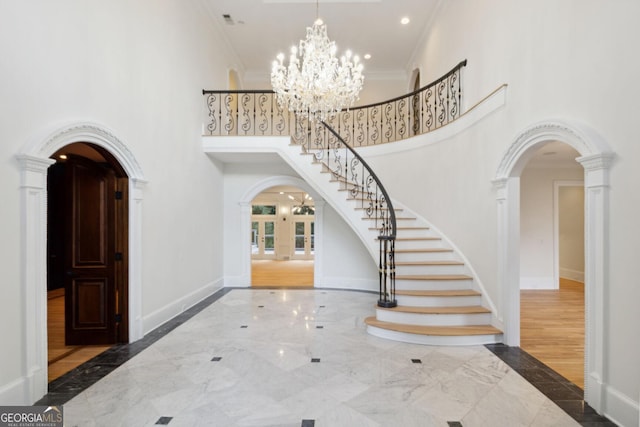 entryway featuring a high ceiling, decorative columns, ornamental molding, and wood-type flooring