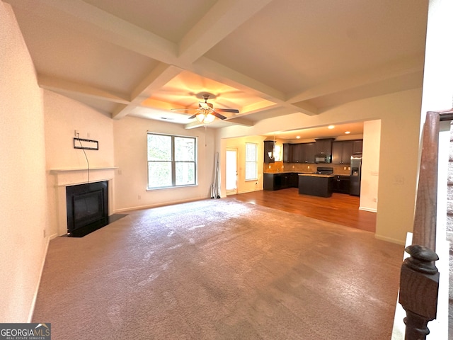 unfurnished living room with coffered ceiling, ceiling fan, beam ceiling, and wood-type flooring