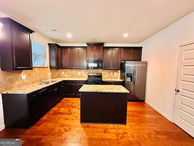 kitchen with light hardwood / wood-style flooring, backsplash, black appliances, a kitchen island, and sink