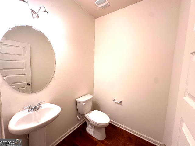 bathroom featuring toilet, sink, and wood-type flooring