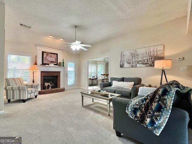 carpeted living area with a textured ceiling, plenty of natural light, and a fireplace