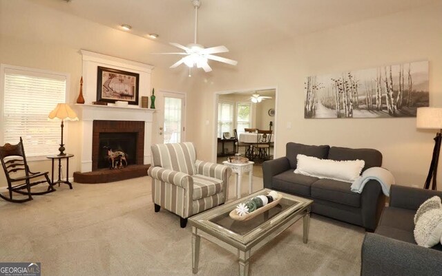 carpeted living room with a brick fireplace and a ceiling fan