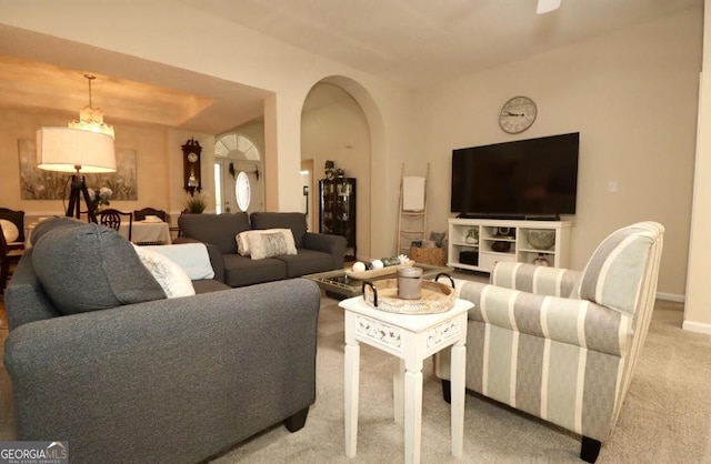 living room with arched walkways, light colored carpet, and baseboards