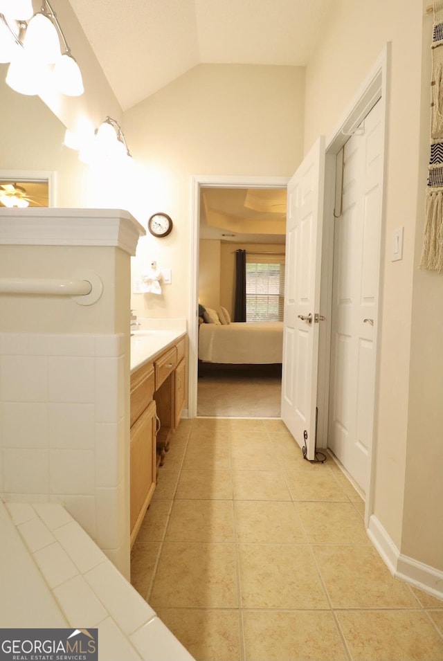 ensuite bathroom featuring ensuite bathroom, vaulted ceiling, tile patterned flooring, and vanity