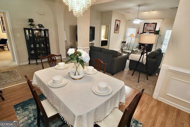 dining area featuring ceiling fan with notable chandelier, a fireplace, wood finished floors, and lofted ceiling