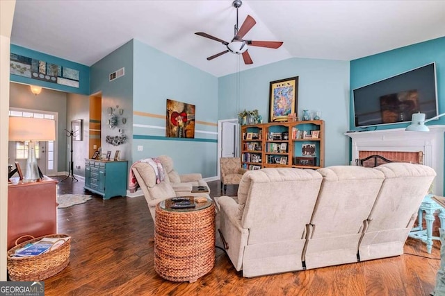 living room with lofted ceiling, ceiling fan, dark hardwood / wood-style flooring, and a brick fireplace