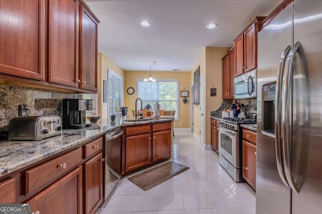 kitchen with stone countertops, stainless steel appliances, sink, and decorative backsplash