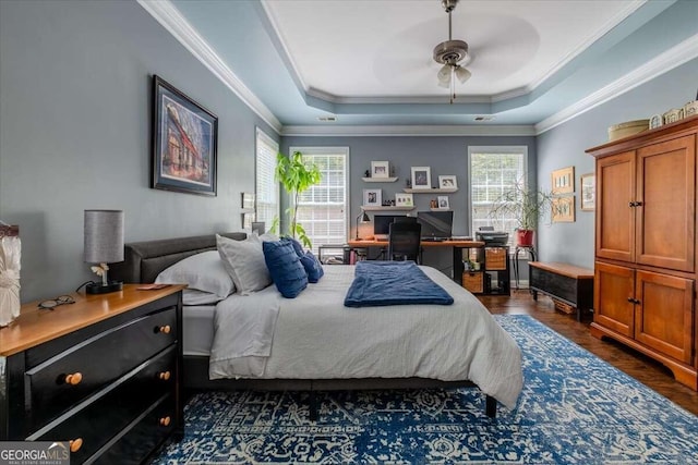 bedroom featuring a tray ceiling, dark wood-type flooring, ornamental molding, and ceiling fan