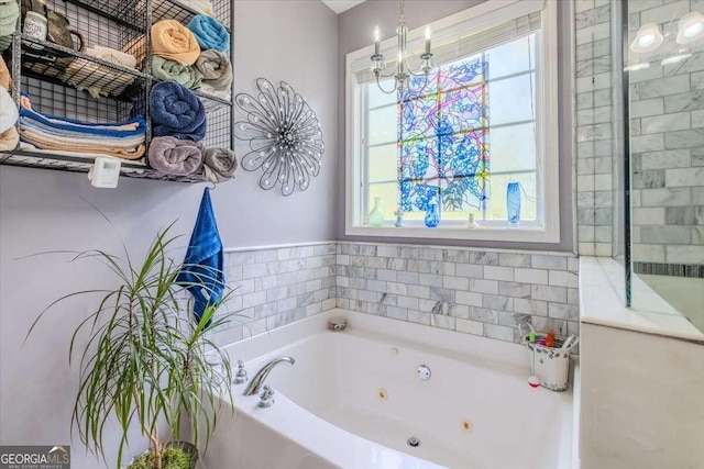 bathroom with a tub to relax in, a wealth of natural light, and an inviting chandelier