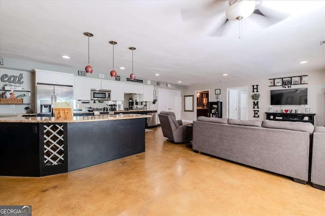 kitchen featuring white cabinets, light stone counters, stainless steel appliances, ceiling fan, and pendant lighting