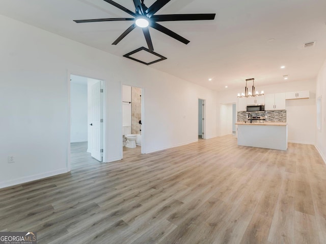 unfurnished living room with ceiling fan with notable chandelier and light hardwood / wood-style flooring