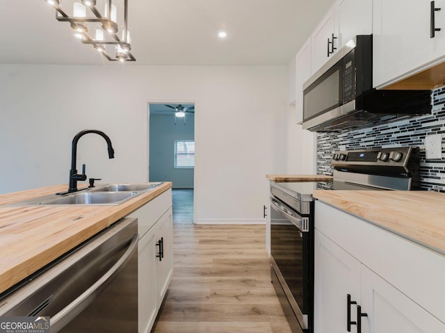 kitchen with pendant lighting, sink, light hardwood / wood-style floors, white cabinetry, and stainless steel appliances