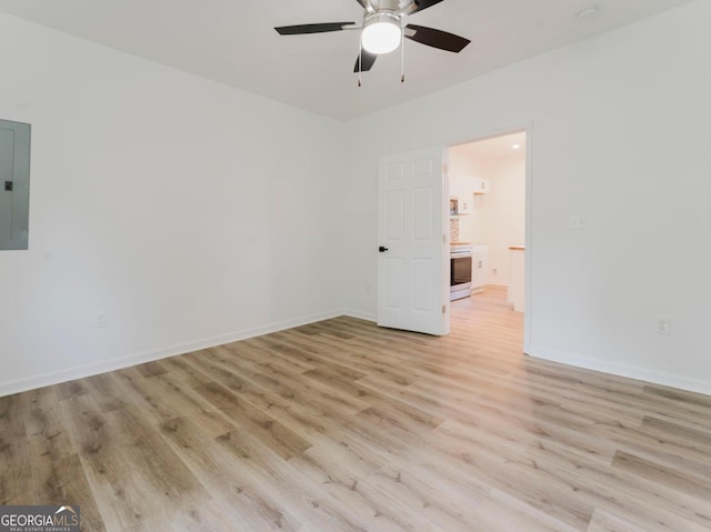 spare room featuring ceiling fan, light wood-type flooring, and electric panel