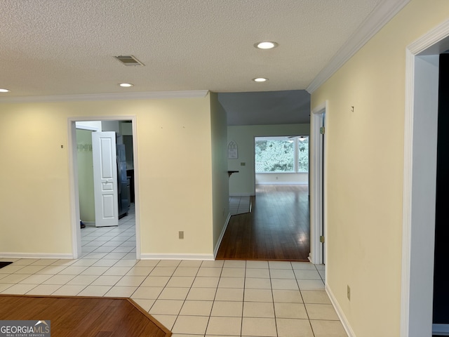 hall with a textured ceiling, ornamental molding, and light wood-type flooring