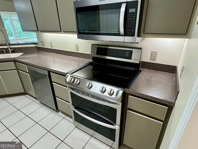 kitchen with appliances with stainless steel finishes, light tile patterned floors, and sink