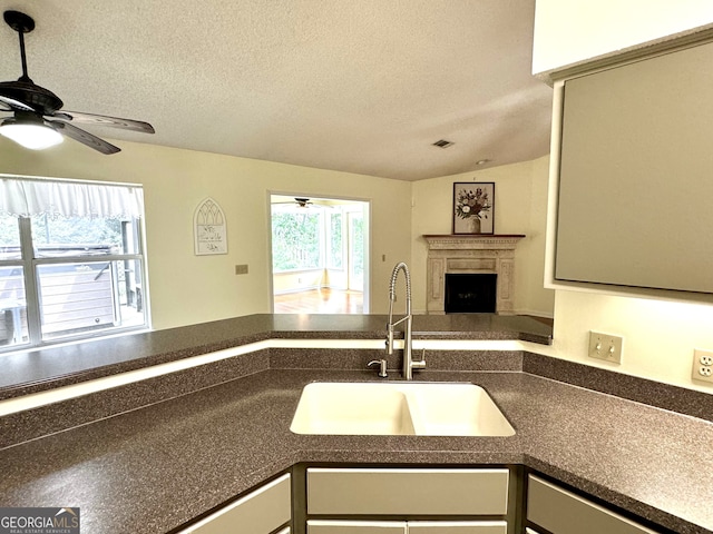 kitchen featuring a textured ceiling, ceiling fan, sink, and lofted ceiling