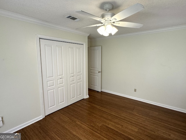 unfurnished bedroom with ornamental molding, a textured ceiling, dark hardwood / wood-style flooring, ceiling fan, and a closet