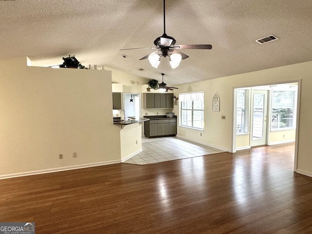 unfurnished living room with lofted ceiling, light hardwood / wood-style flooring, ceiling fan, and a textured ceiling