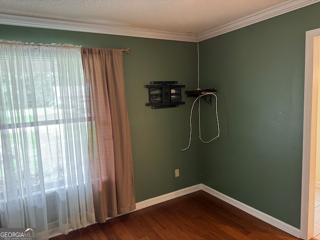 empty room featuring a textured ceiling, ornamental molding, and hardwood / wood-style flooring