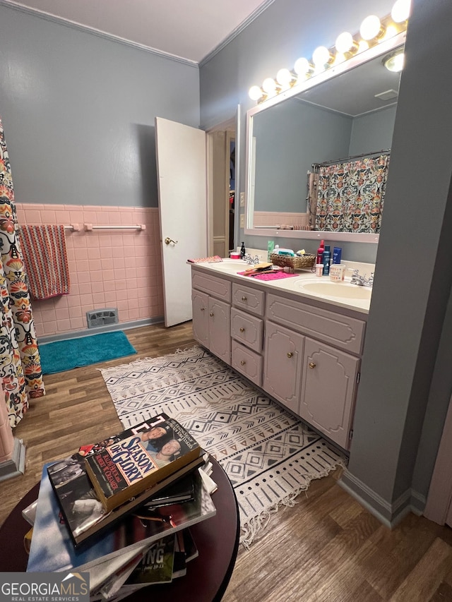 bathroom with hardwood / wood-style floors, ornamental molding, tile walls, and vanity