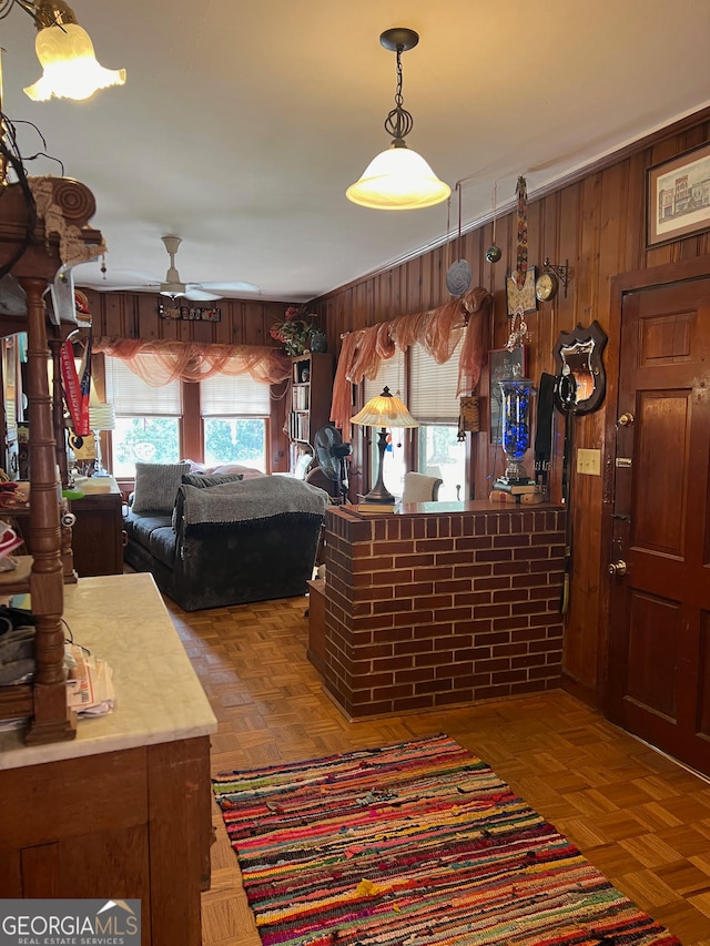 interior space featuring parquet floors, wood walls, and ceiling fan