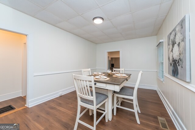 dining area featuring dark hardwood / wood-style flooring and a drop ceiling