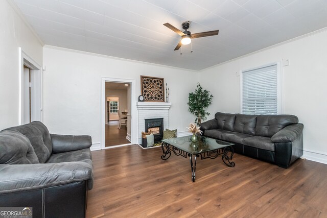 living room featuring ornamental molding, dark hardwood / wood-style flooring, a brick fireplace, and ceiling fan