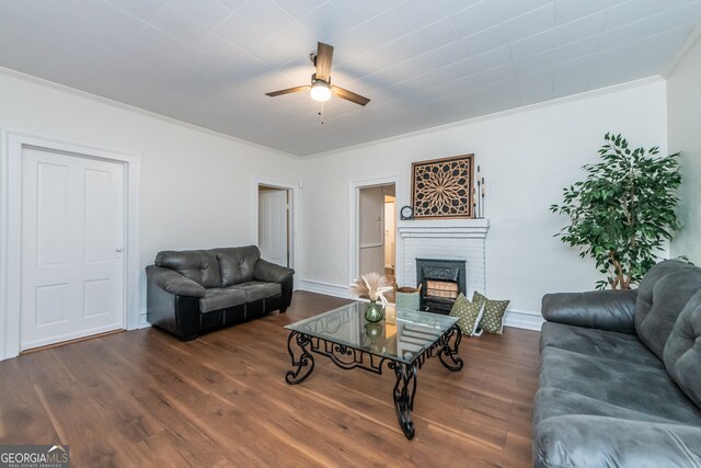 living room featuring a fireplace, dark wood-type flooring, ornamental molding, and ceiling fan