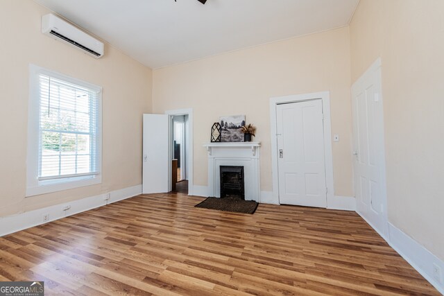 unfurnished living room featuring light hardwood / wood-style flooring and a wall mounted air conditioner