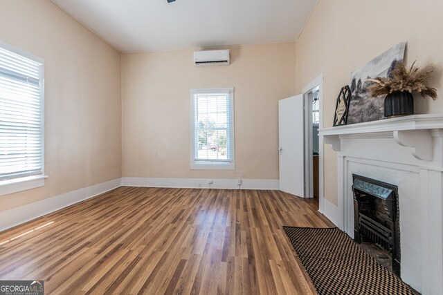 unfurnished living room with wood-type flooring and a wall mounted air conditioner