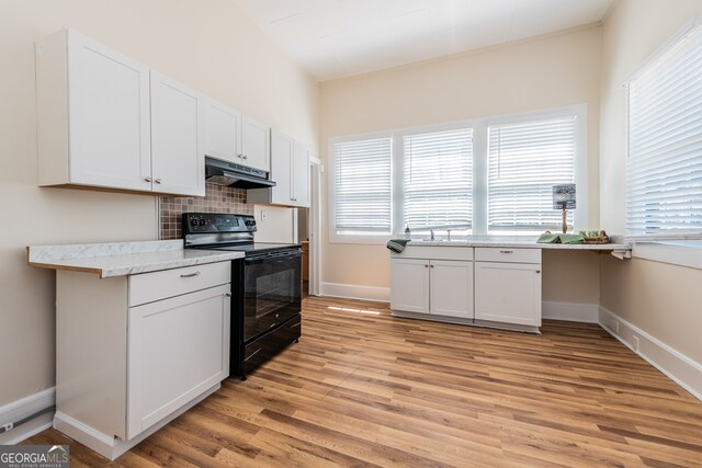 kitchen with backsplash, light wood-type flooring, electric range, light stone counters, and white cabinetry