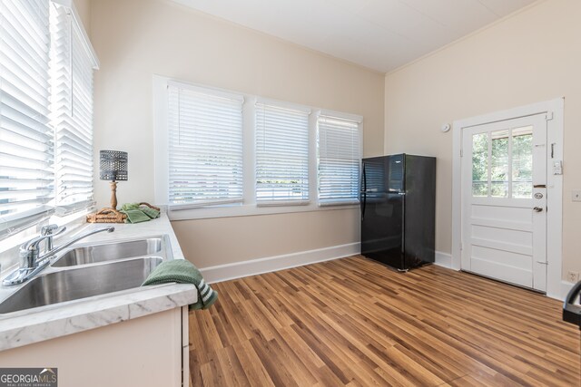 kitchen featuring crown molding, hardwood / wood-style flooring, black refrigerator, and sink