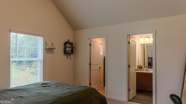 bedroom with sink, connected bathroom, vaulted ceiling, and light carpet