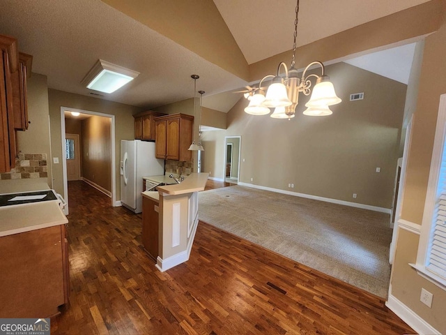 kitchen with kitchen peninsula, a chandelier, dark wood-type flooring, pendant lighting, and vaulted ceiling