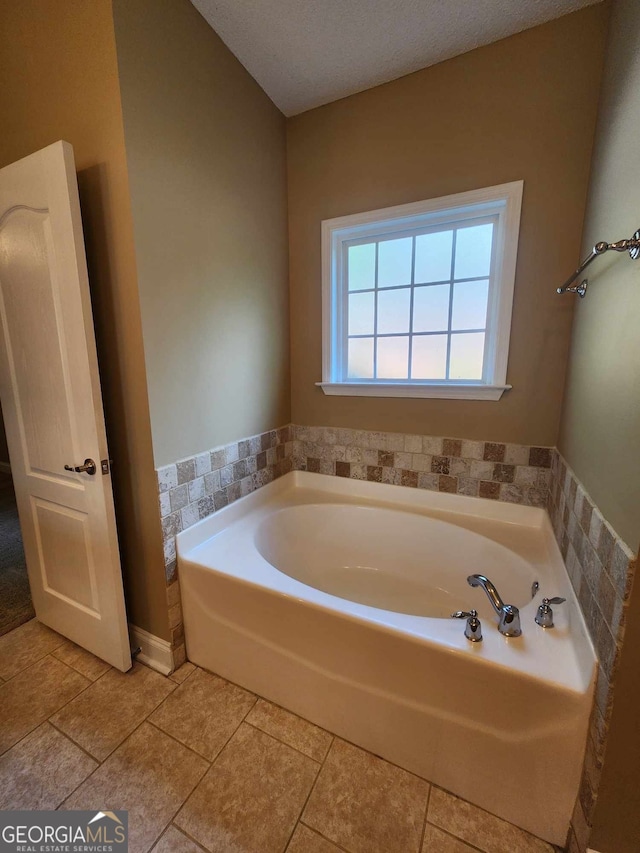 bathroom with a tub, tile patterned flooring, and a textured ceiling