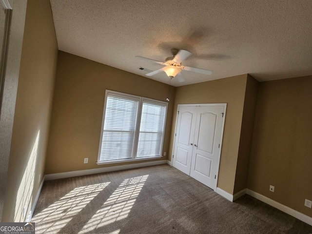 unfurnished bedroom with ceiling fan, a textured ceiling, a closet, and carpet