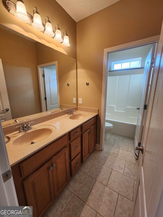 bathroom with toilet, vanity, a textured ceiling, and tile patterned floors