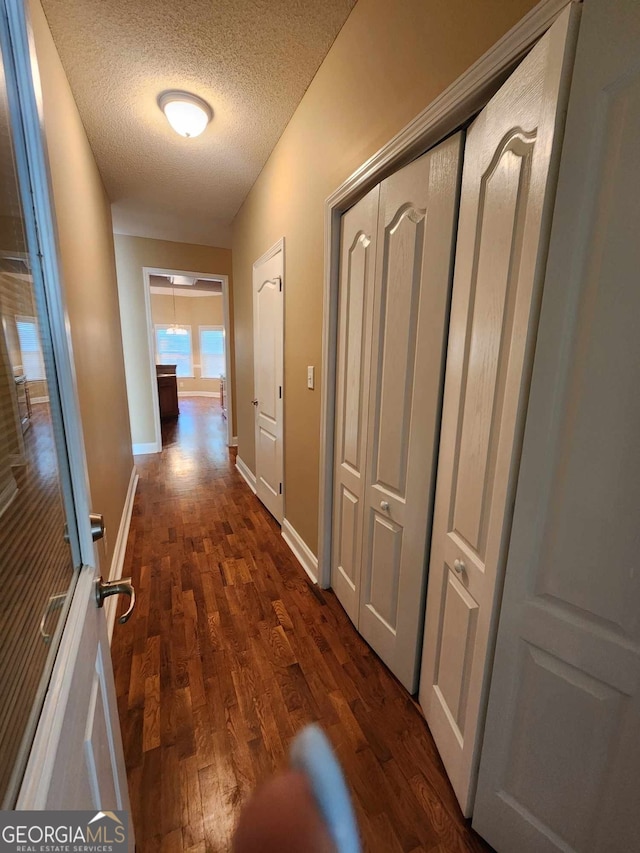 corridor with dark wood-type flooring and a textured ceiling