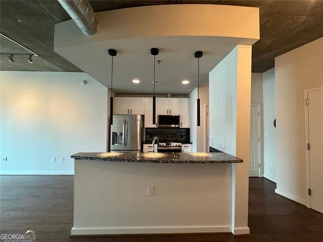 kitchen with appliances with stainless steel finishes, dark stone counters, white cabinetry, and pendant lighting