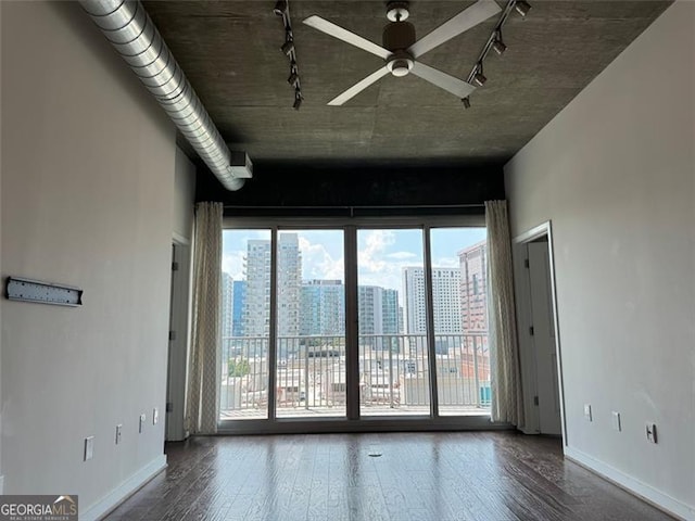 empty room with ceiling fan, dark hardwood / wood-style floors, and track lighting