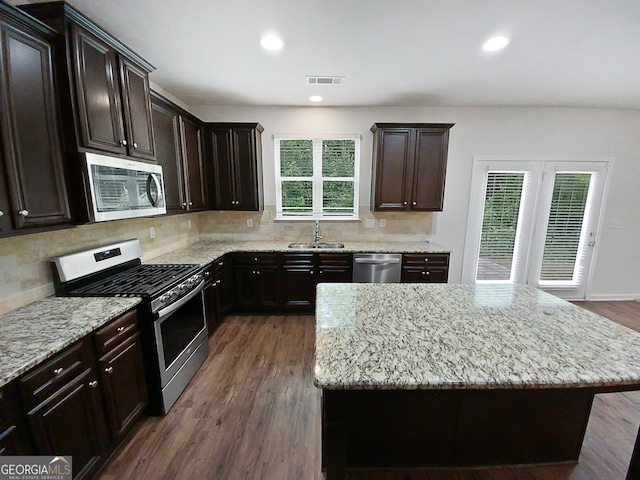 kitchen featuring light stone countertops, visible vents, a sink, appliances with stainless steel finishes, and backsplash