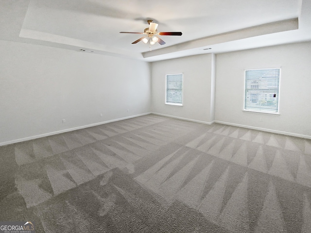 empty room with baseboards, carpet, a tray ceiling, and a ceiling fan