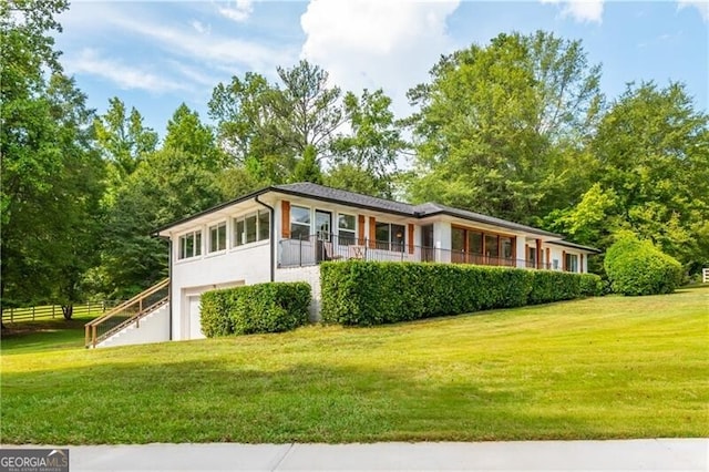 ranch-style house with stucco siding, an attached garage, fence, and a front lawn